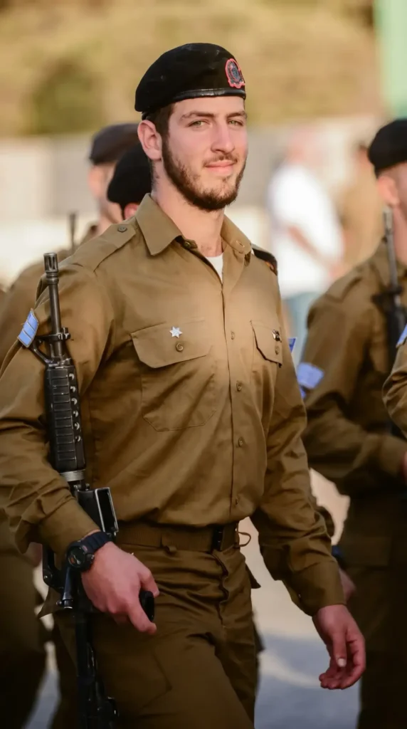 החייל נבו פישר הי"ד עומד זקוף ואוחז בנשקו במהלך מסדר צבאי.